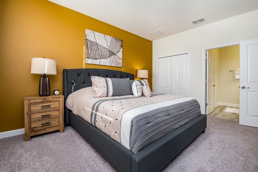 A bedroom with a bed, bedside tables, a wall art piece, and a door.