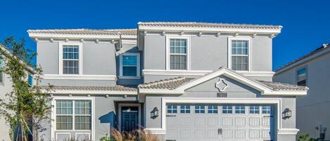 A two-story house with a garage, a front door, and a small porch area.