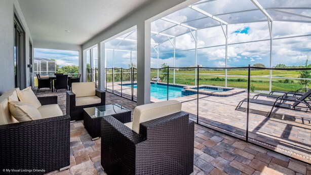 A covered outdoor area with wicker furniture, a pool, and a view of the landscape. - 9 Bedroom Champions Gate Resort (Davenport)