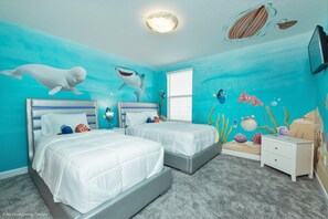 A bedroom with two beds, a nightstand, and a dresser. The room has a blue ocean-themed mural on the walls. - 9 Bedroom Champions Gate Resort (Davenport)