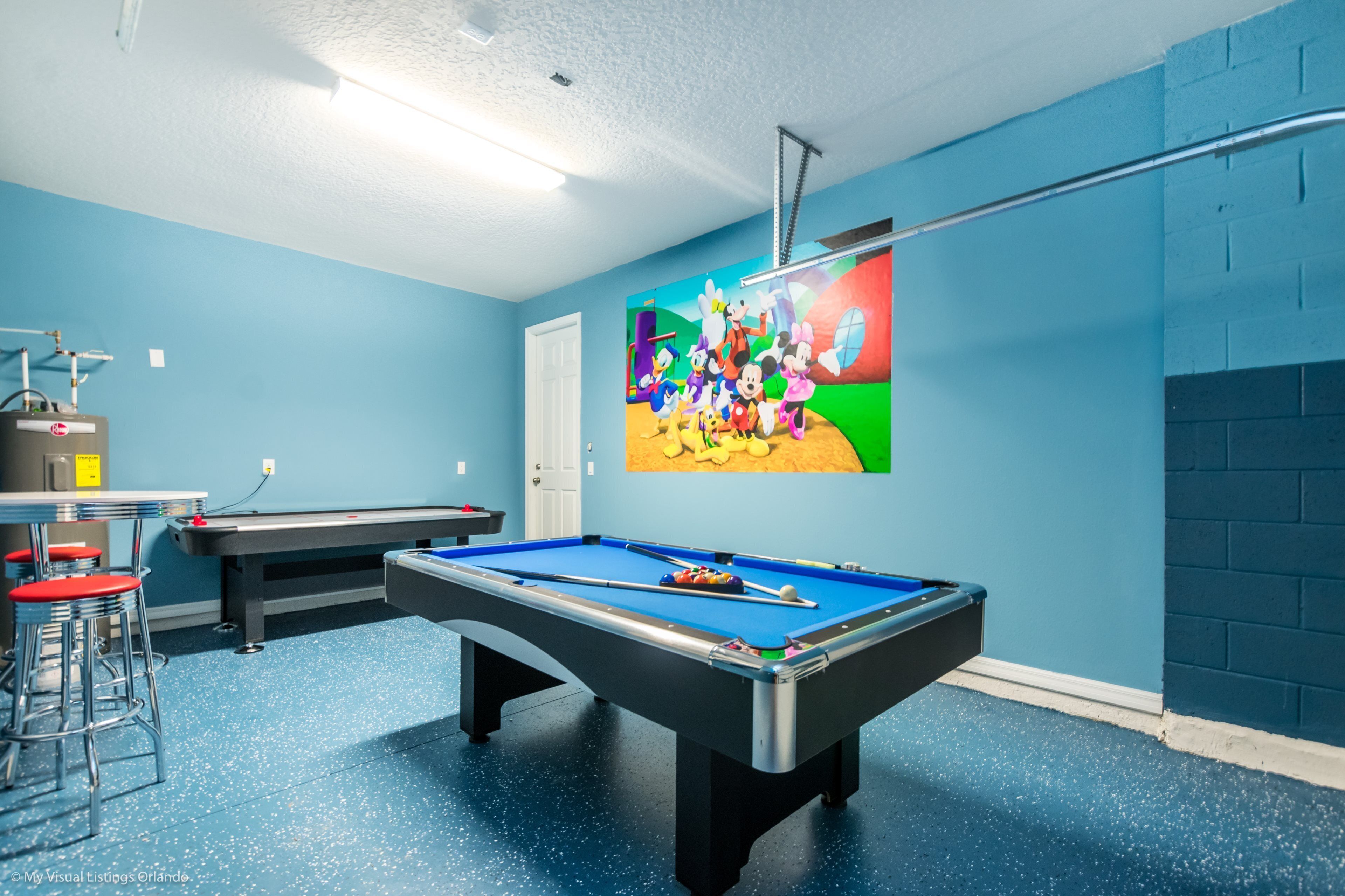 Een pooltafel met een kleurrijke muurschildering, een bar en een blauwe wand.