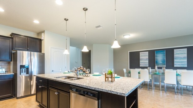 A modern kitchen with stainless steel appliances, granite countertops, and pendant lighting. - Ultimate New 8 Bedroom 6 Bathroom Windsor (Kissimmee)