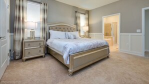 A bedroom with a bed, nightstands, a ceiling fan, and a bathroom door. - Ultimate New 8 Bedroom 6 Bathroom Windsor (Kissimmee)