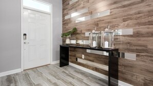 Um corredor moderno com porta branca, mesa consola com objetos decorativos e uma parede de madeira como destaque.