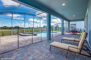Ein überdachter Außenbereich mit Pool, Liegestühlen und einem Patio-Tisch.