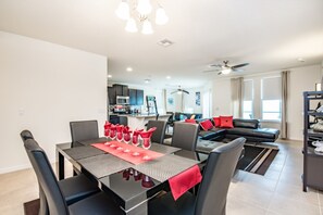A modern living room with a dining area, a kitchen, and a seating area with a sofa and chairs. - 4 Bedroom 3 Bathroom Villa (Davenport)