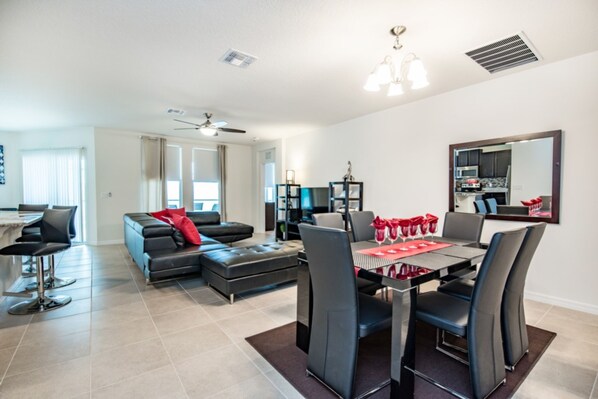 A modern living room with a dining area, a sofa, a coffee table, and a dining table with chairs.