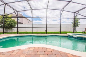 A swimming pool with a brick deck and a covered area.