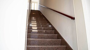 Un escalier avec des marches en granit et une rampe, menant à une porte située en haut.