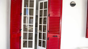 Une porte rouge avec des panneaux de verre et un luminaire noir fixé au mur.