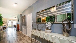 A modern hallway with a white console table, decorative mirrors, and a potted orchid. - 1314bw00 (Davenport)