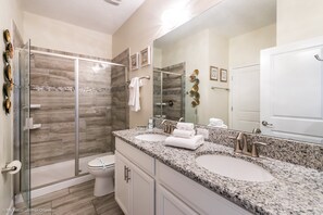A modern bathroom with a glass-enclosed shower, two sinks, and a large mirror. - 1314bw00 (Davenport)
