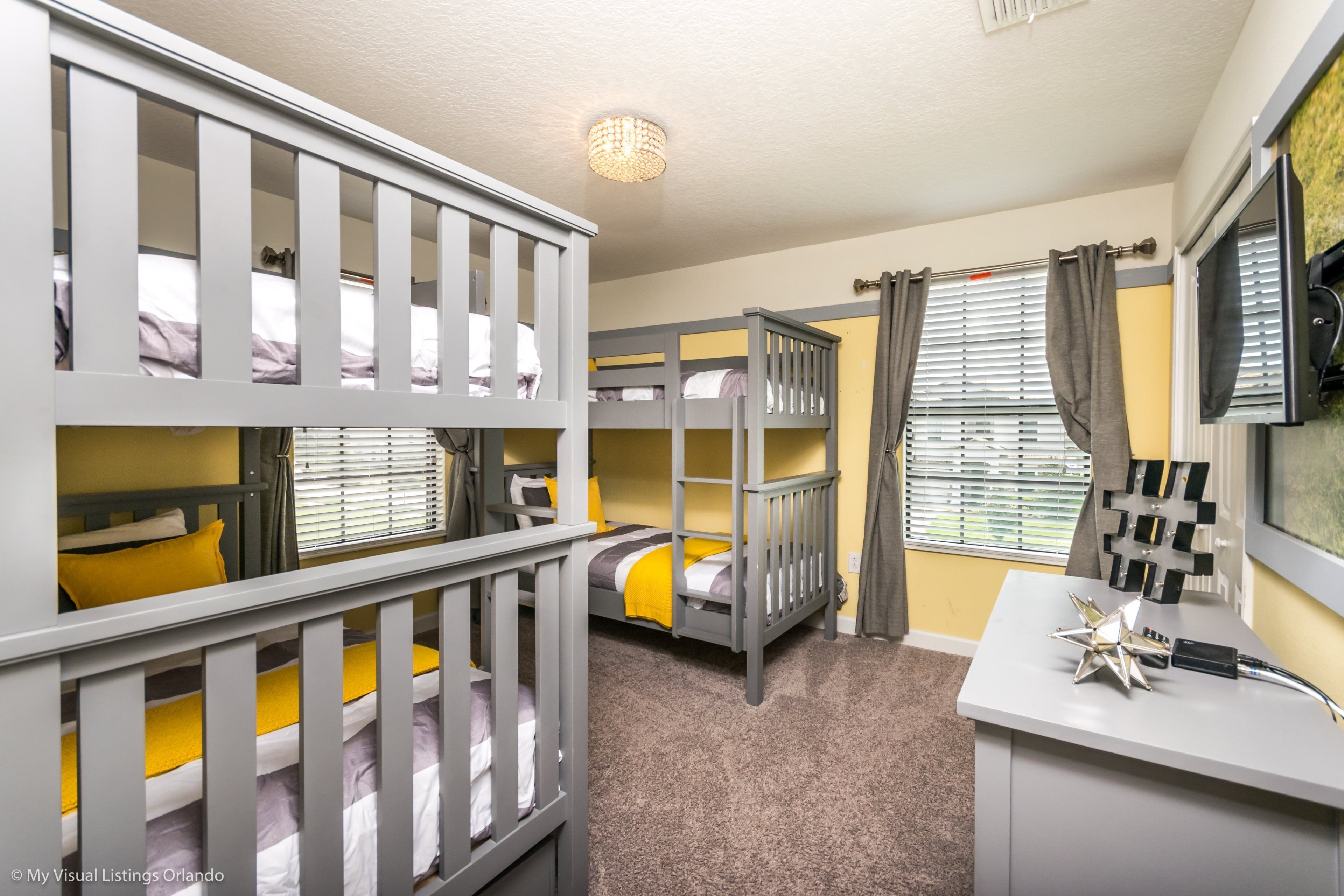 A room with bunk beds, a desk, and a window with curtains.