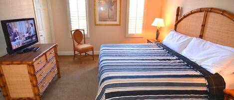 A bedroom with a bed, a dresser, a chair, and a television.