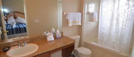 A bathroom with a sink, mirror, toilet, and shower curtain.