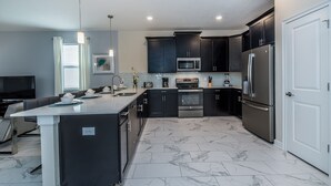 A modern kitchen with dark cabinets, stainless steel appliances, and a marble floor. - 8 Bdrm 5 Bath Villa (Davenport)
