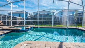 A swimming pool with a glass enclosure, surrounded by a patio area and a view of residential buildings. - 8 Bdrm 5 Bath Villa (Davenport)