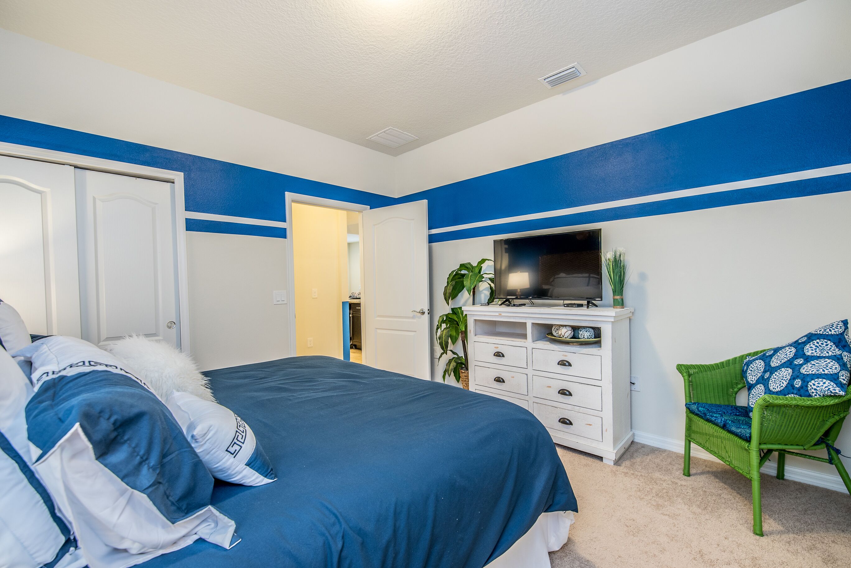 A bedroom with a bed, a dresser, a television, and a chair.