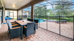 A covered patio area with a pool, outdoor furniture, and a view of the backyard. - 9 Bedroom 5 Bathroom Champions Gate Resort (Davenport)