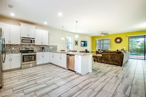 A modern kitchen with white cabinets, stainless steel appliances, and a large island.