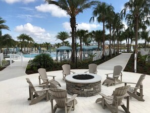 A poolside area with Adirondack chairs and a circular stone fire pit. - Luxury Solara 7 Bed Private Pool IHR 1039 (Kissimmee)