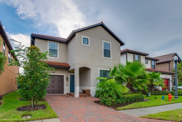 A two-story house with a brick driveway, a front porch, and a garage.