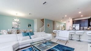 Una sala de estar moderna con un sofá blanco, una mesa de centro de vidrio y un tapete azul.