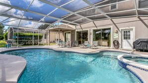 Ein Schwimmbecken mit überdachter Terrasse, Liegestühlen und einem Whirlpool.