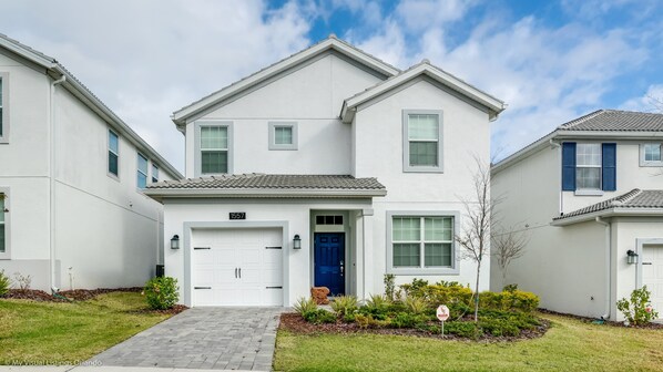A two-story residential building with a white exterior, a blue front door, and a garage.