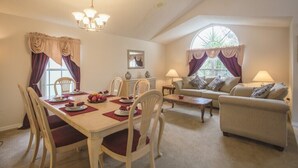 Un coin repas avec une table dressée pour quatre personnes, un canapé et une fenêtre avec des rideaux.