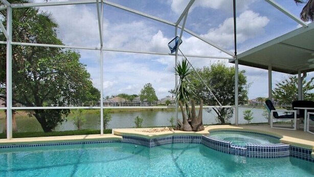 Une piscine à l’eau d’un bleu cristallin, entourée d’une zone abritée d’où l’on peut admirer un lac et des arbres.