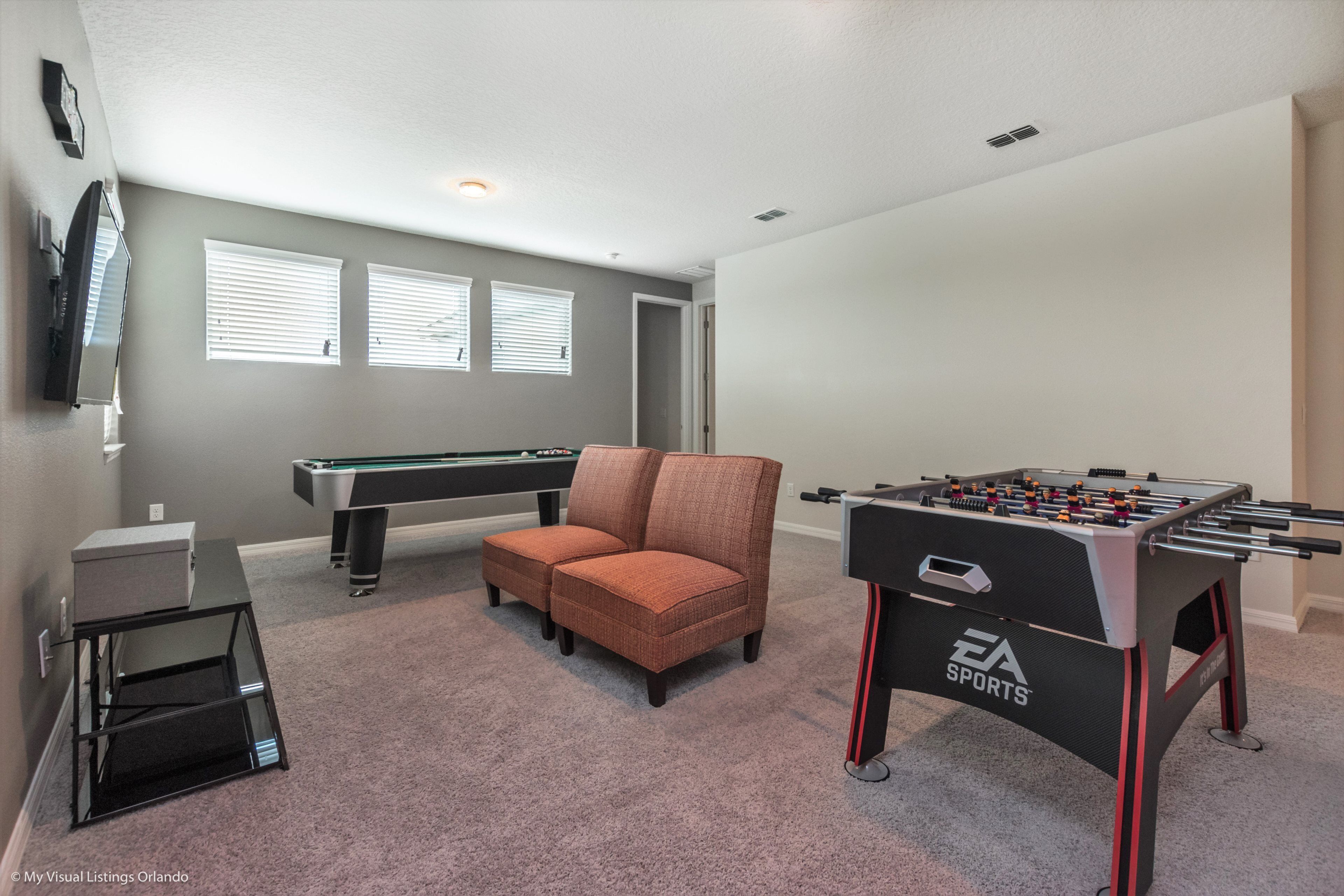 Una habitación con mesa de billar, mesa de futbolín y una zona de estar cómoda.