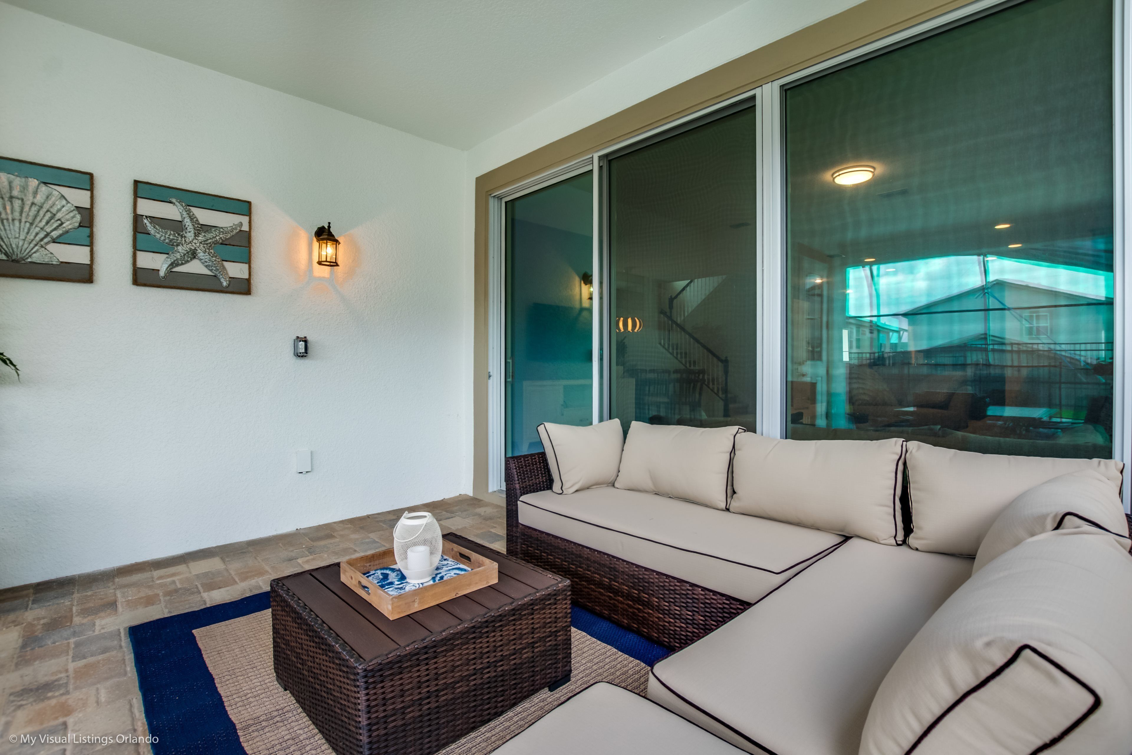 A modern living room with a large sliding glass door, a wicker sofa, and a wooden coffee table.
