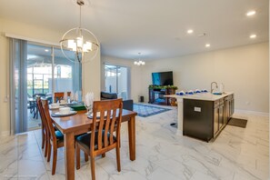 Una cocina moderna con una isla central, un comedor con sillas de madera y un amplio ventanal corredero que da a un patio exterior.