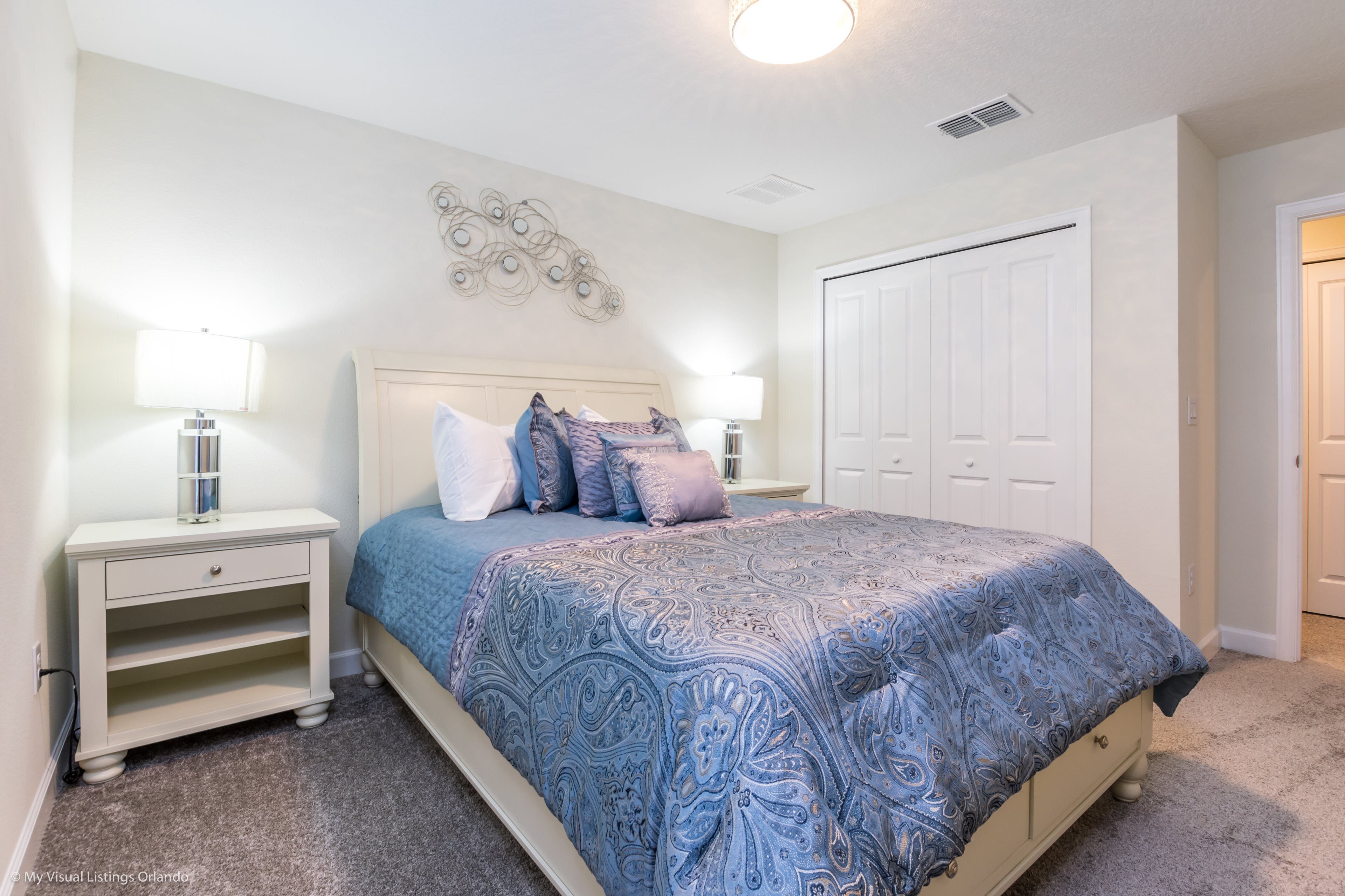 A bedroom with a bed, nightstands, a dresser, and a closet.