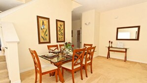A dining area with a glass table, wooden chairs, and framed artwork on the walls. - 1915msd (Clermont)