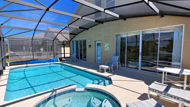 A covered outdoor swimming pool with lounge chairs and a hot tub. - 1915msd (Clermont)