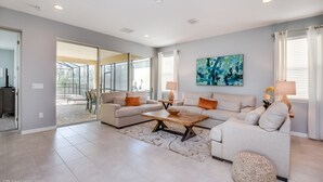 A spacious living room with a large sofa set, a coffee table, and a painting on the wall. - 7 Bedroom 5 Bathroom with Spa & Game Room (Kissimmee)