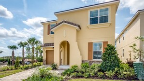 A two-story house with a beige exterior, a front entrance with an archway, and a small porch. - 7 Bedroom 5 Bathroom with Spa & Game Room (Kissimmee)