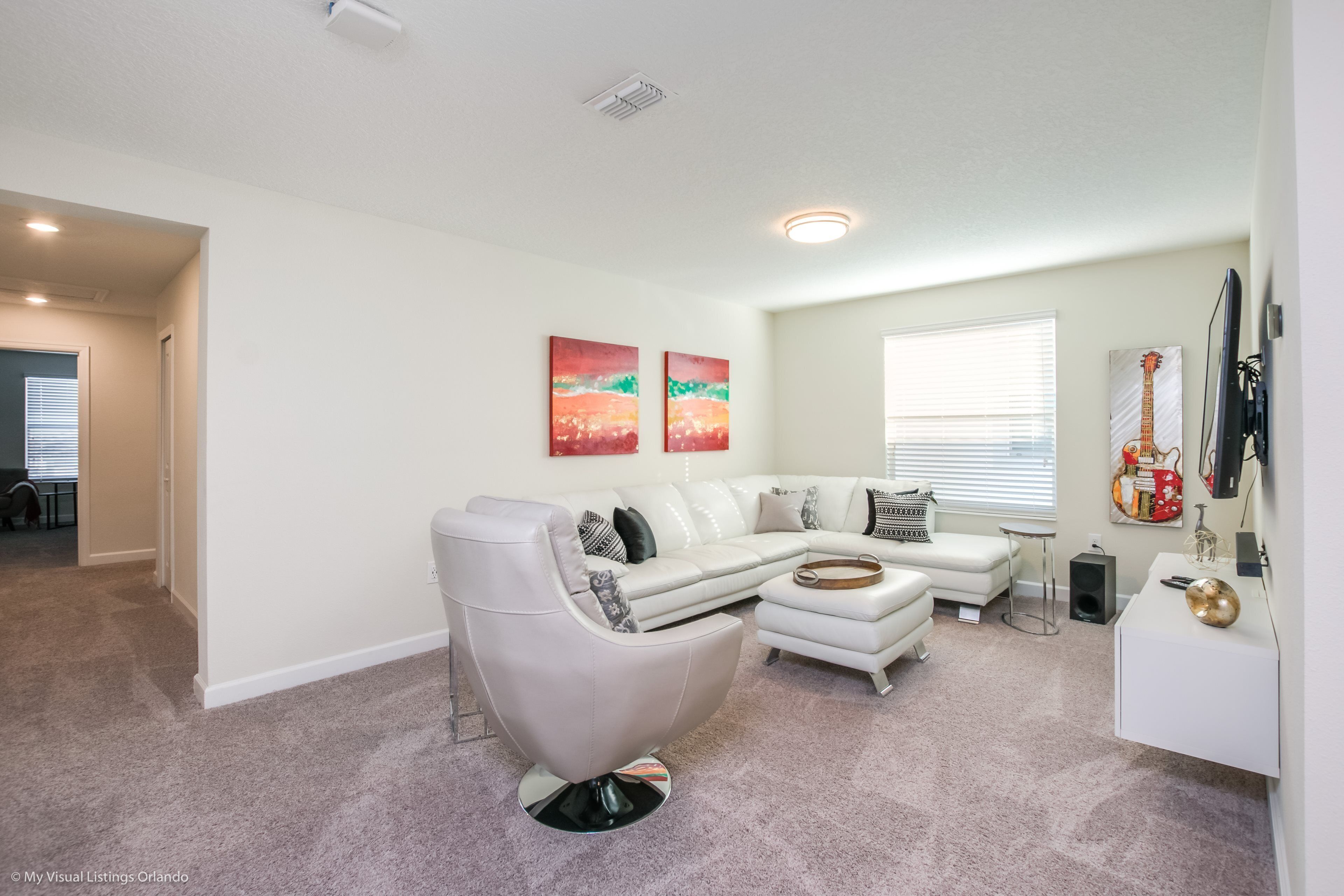 A modern living room with a sectional sofa, a recliner, a coffee table, and a flat-screen TV mounted on the wall.