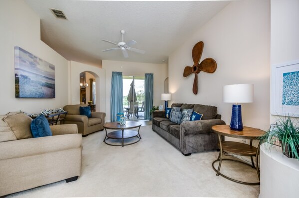 A spacious living room with a ceiling fan, a round coffee table, and two sofas with blue cushions.