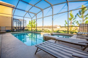 Ein Poolbereich mit Glasveranda, Liegestühlen und Blick auf die umliegende Landschaft.