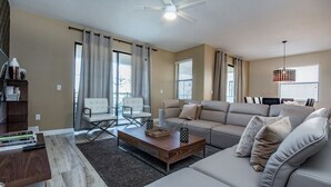 A modern living room with a sofa, coffee table, and a ceiling fan. - 6bed 4Ba Villa Game Room Pool Spa (Davenport)