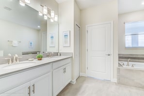 A modern bathroom with two sinks, a large mirror, and a bathtub. - 8823inter (Davenport)