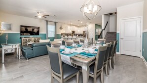 A dining area with a table set for six, a sofa, and a kitchen in the background. - 8823inter (Davenport)