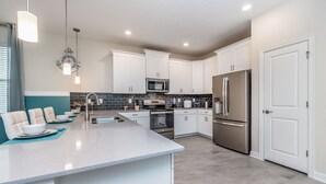 A modern kitchen with white cabinets, stainless steel appliances, and a central island. - 8823inter (Davenport)