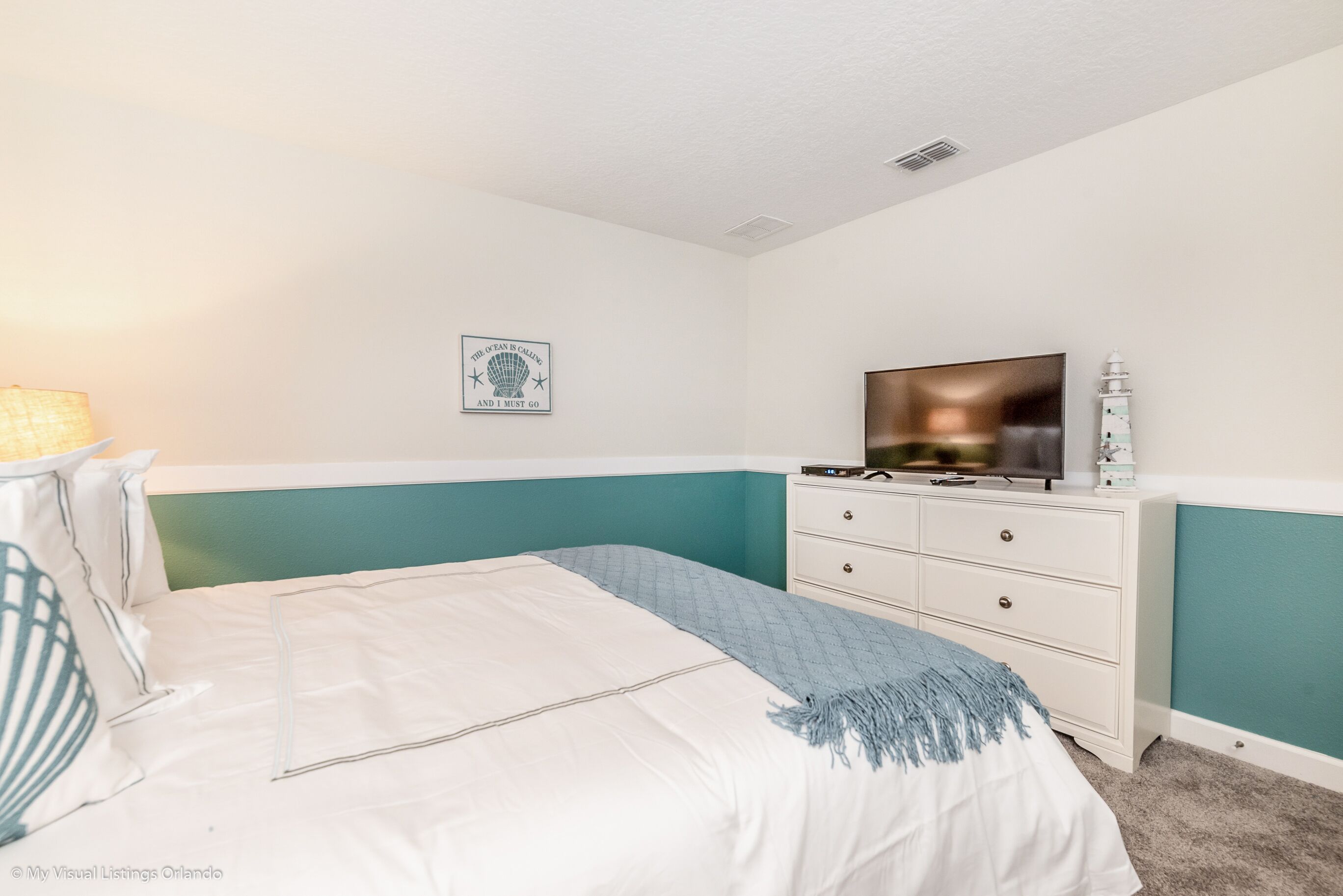 A bedroom with a bed, a dresser, a television, and a wall decoration.