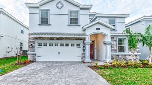 A two-story house with a white exterior, a stone accent wall, a garage, and a well-maintained front yard with plants. - 8823inter (Davenport)