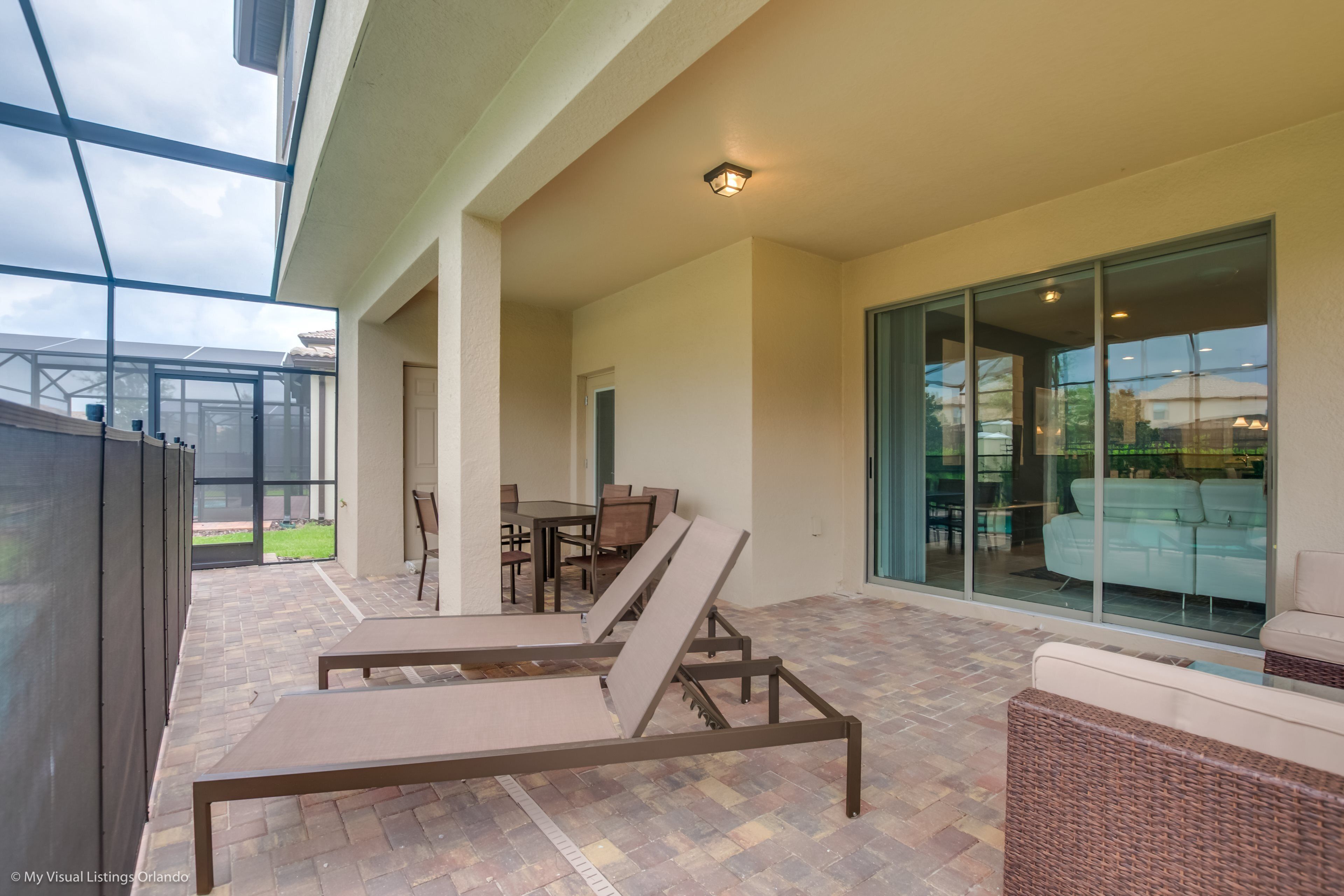 Un espacio de patio cubierto con sillones y una mesa de comedor.