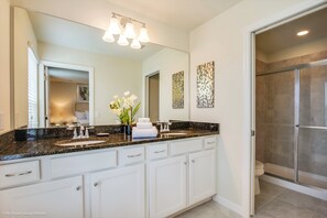 Un bagno moderno con un mobile lavabo doppio, uno specchio grande e una doccia a filo pavimento.